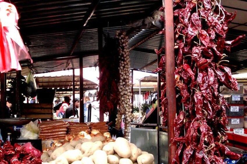 Ein Marktstand mit getrockneten roten Chilischoten und Kartoffeln. 4