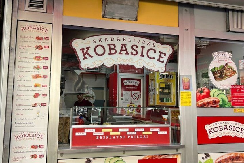 Ein Imbissstand namens 'Kobasice' mit einer Speisekarte und einer Auswahl an Speisen. 5