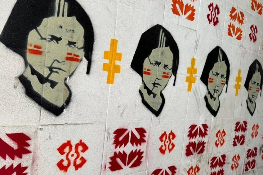 A wall with repeated graffiti of a face and red maple leaf patterns. 5