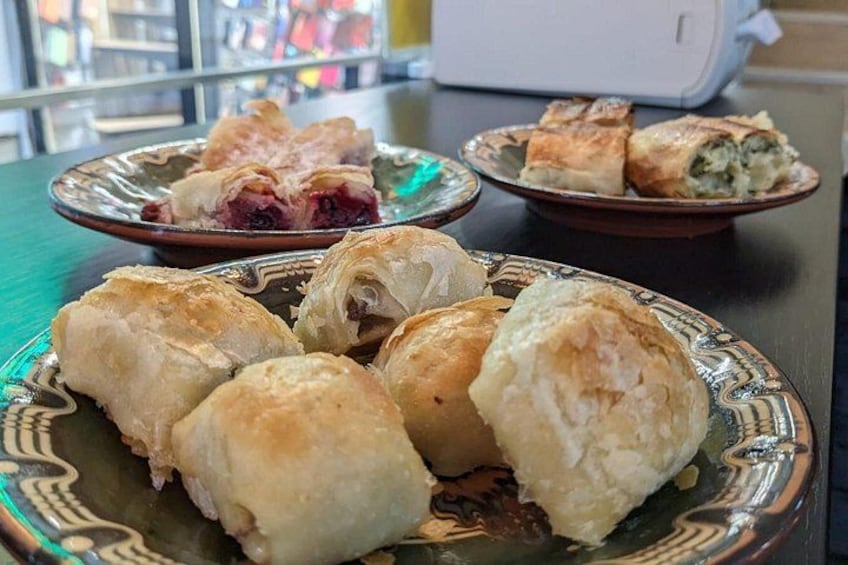 Ein Teller mit Gebäck, darunter Blätterteig und ein Kuchen, auf einem Tisch. 3