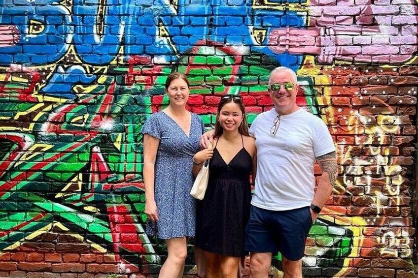 A group of people standing in front of a colorful graffiti wall. 4