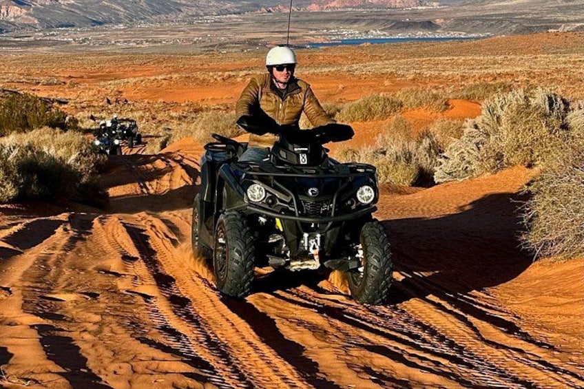 A person riding an ATV on a dirt trail in a desert landscape. 3