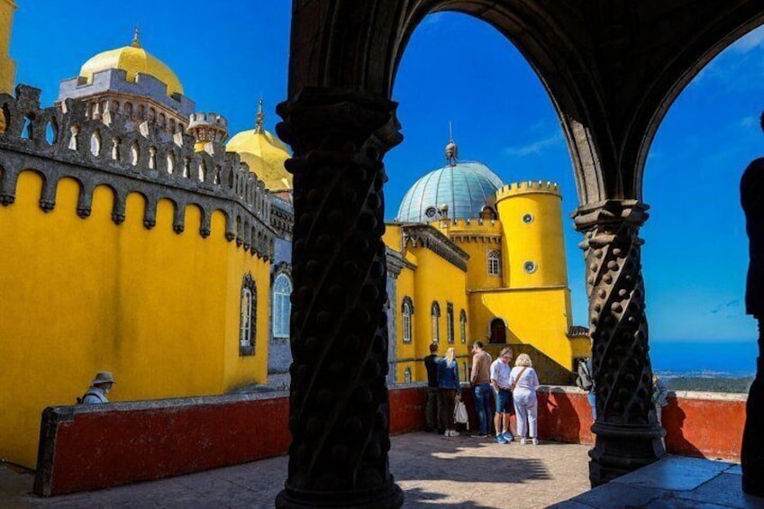 A yellow building with domes, arches, and a red wall. 1