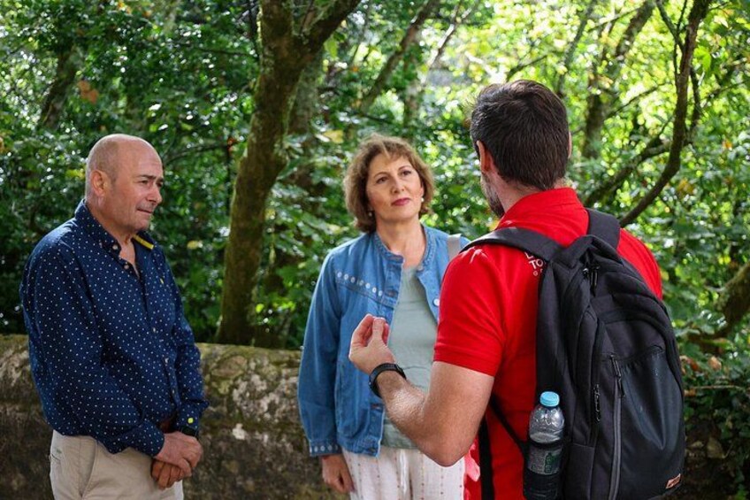 Three people standing outdoors, one wearing a red shirt and a backpack, another in a blue shirt, and the third in a blue polka dot shirt. 3