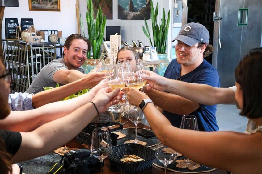 A group of people toasting with wine glasses at a table with a basket of bread. 1