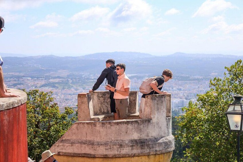 A group of people on a stone platform overlooking a cityscape with mountains in the distance. 2