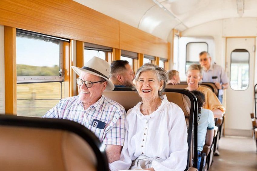 L'intérieur d'un wagon de train avec des passagers assis, des fenêtres et des panneaux de bois. 4