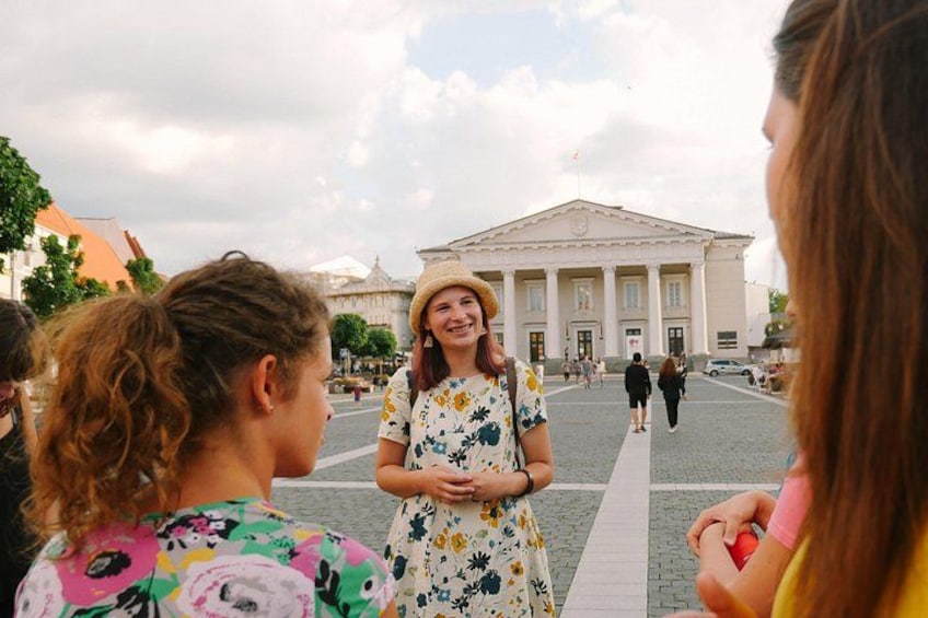 A group of people standing in front of a large building with columns. 1