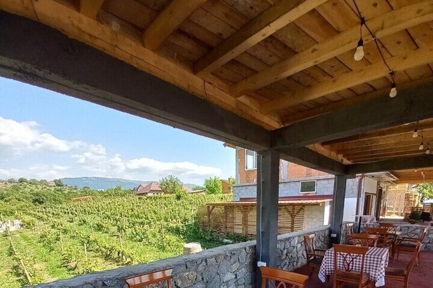 Una pérgola de madera con mesas y sillas que da a un viñedo. 4