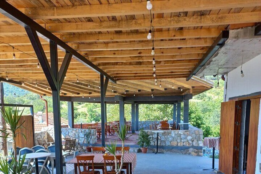 Un patio al aire libre con vigas de madera, mesas, sillas y plantas en macetas. 3