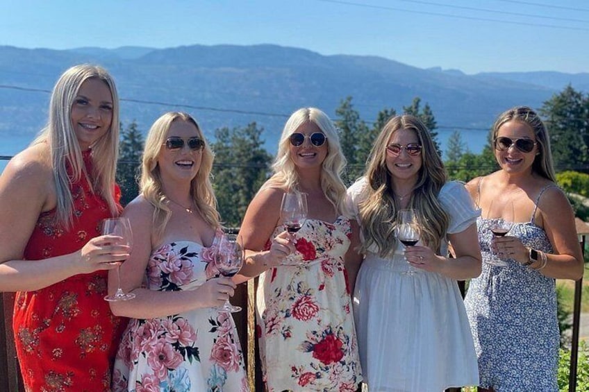 A group of women in floral dresses standing outdoors with a mountainous landscape in the background. 5