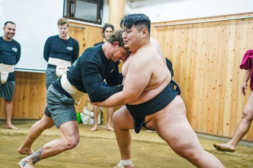 To sumobrydere i en ring, med andre mennesker i baggrunden. 2