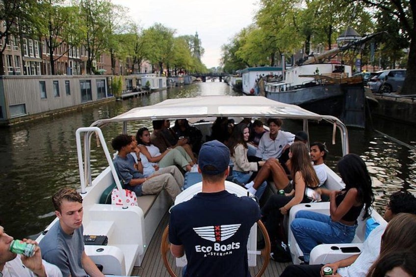 Un groupe de personnes se trouve sur un bateau doté d’un auvent, entouré d’eau et de bâtiments. 2
