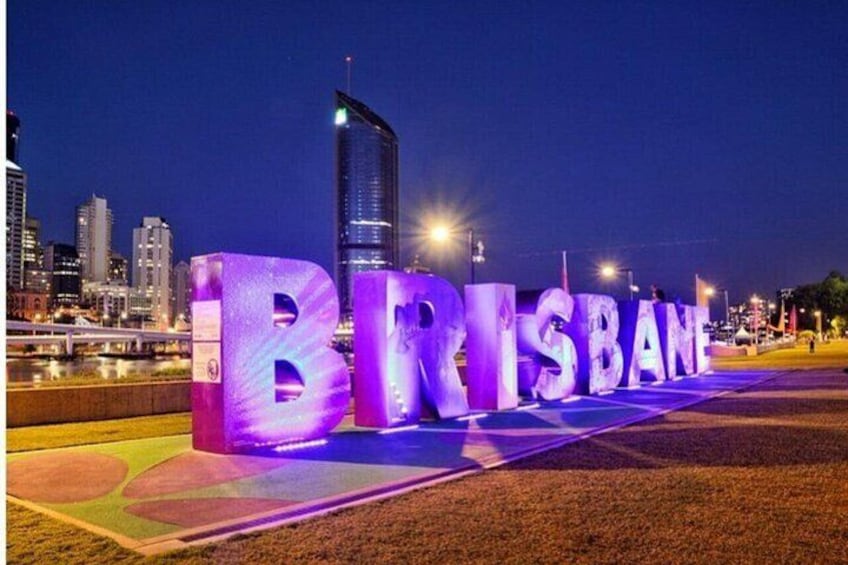 Illuminated letters spelling 'BRISBANE' on a grassy area with a city skyline in the background. 4