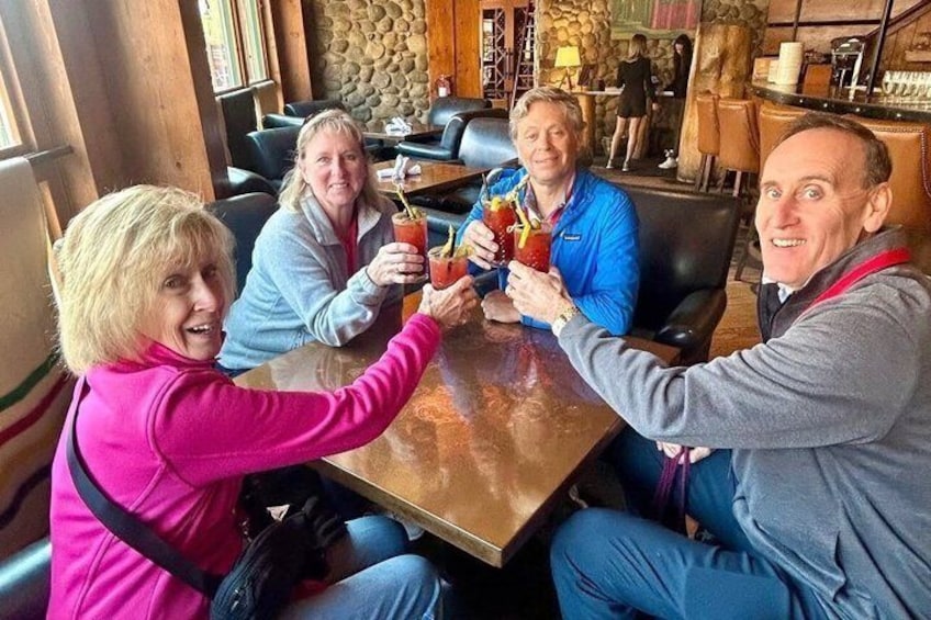 Fire personer sidder ved et bord på en restaurant, hver med en cocktail i hånden. 5