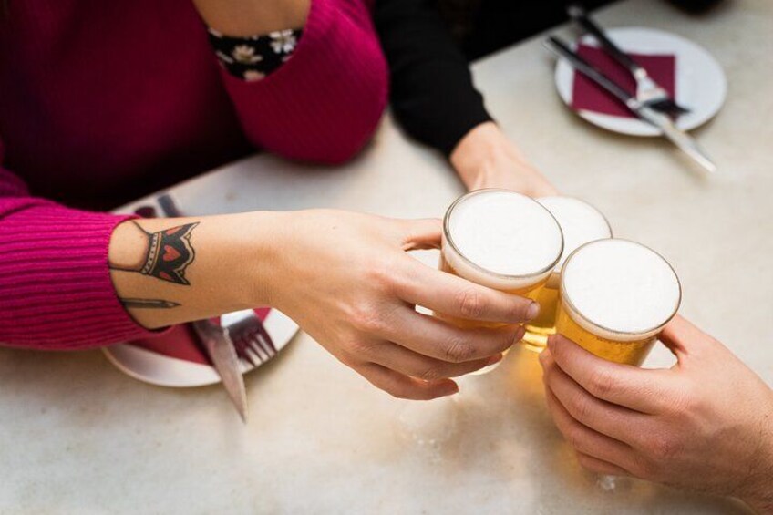Dos personas brindando con vasos de cerveza en una mesa. 3