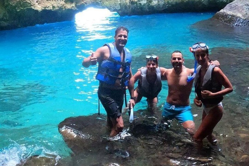 Een groep mensen in helderblauw water, sommigen dragen reddingsvesten en snorkelspullen. 5