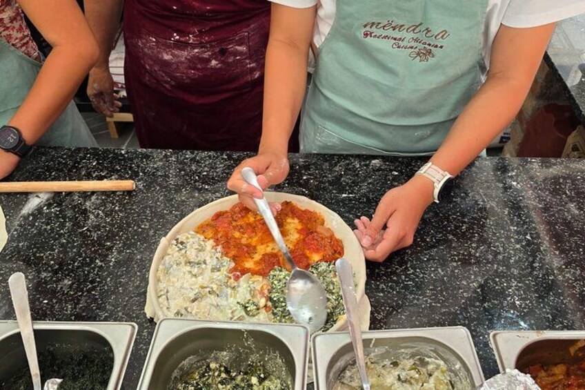 A person preparing food, with a bowl of sauce and a spoon on a countertop. 1