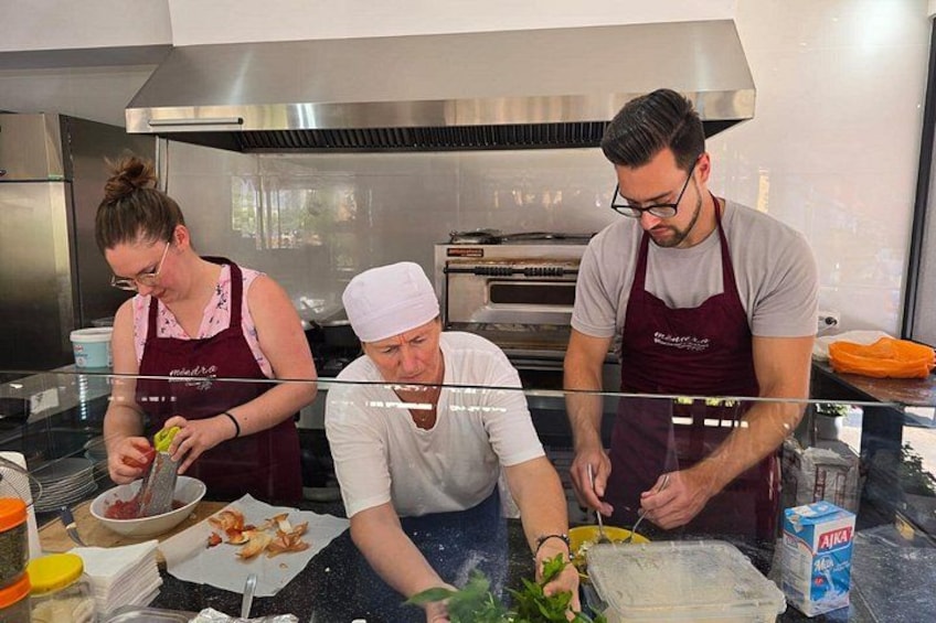 Three people in a kitchen preparing food. 4