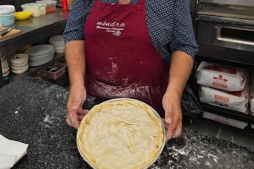A person in a kitchen holding a pie crust. 2