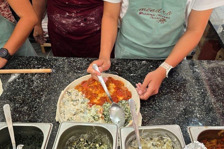 A person preparing food, with a bowl of sauce and a spoon on a countertop. 1