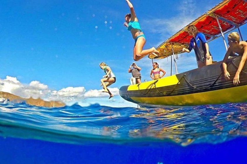 A person jumping off a boat into the water, a boat with a red canopy, and a clear blue sky. 3