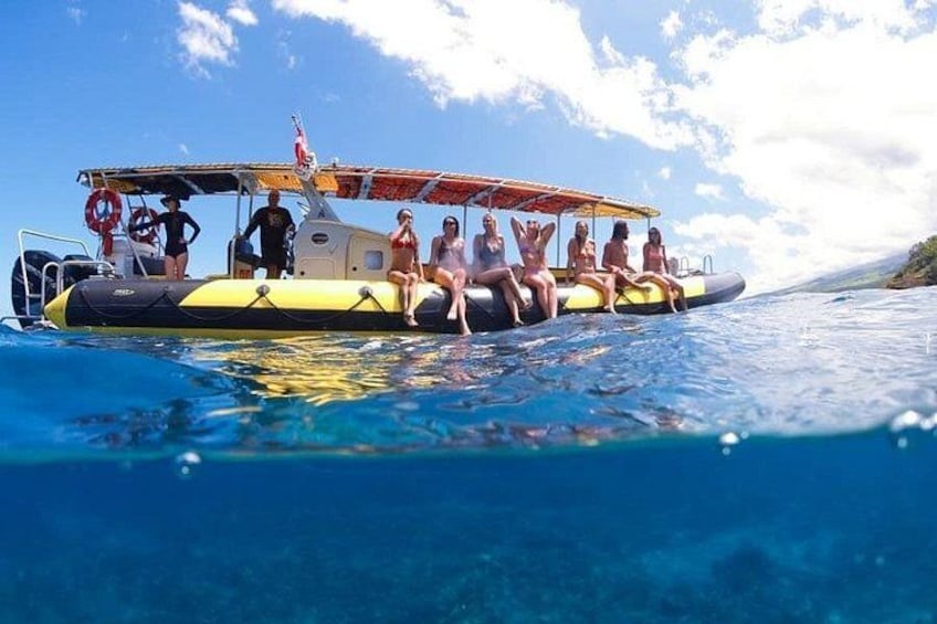 A group of people on a yellow inflatable boat in clear blue water. 2