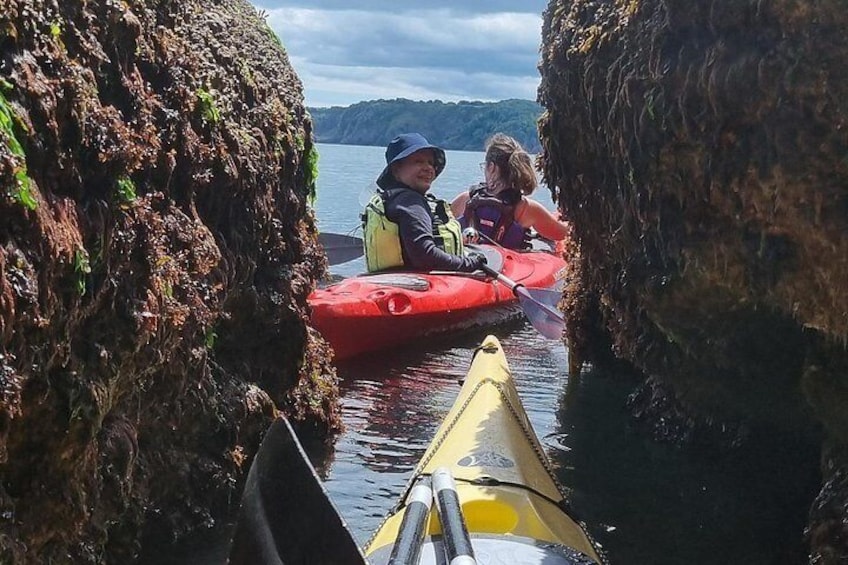 Kayakers in a narrow waterway between rocky cliffs. 3