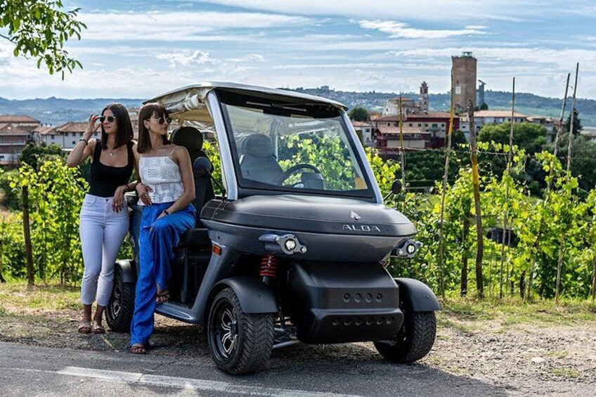 A black ALBA golf cart parked on a road with vineyards in the background. 5