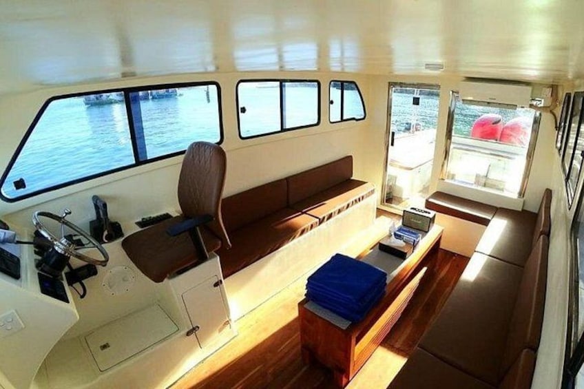 A boat's interior with a steering wheel, windows, and seating areas. 2
