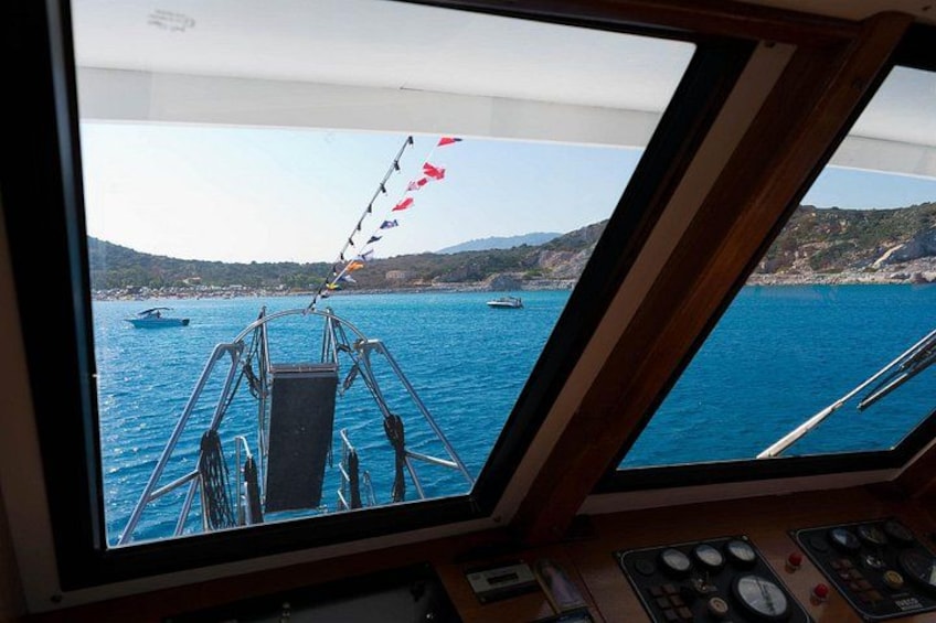 A boat's control panel and a view of the sea with boats and a coastline. 3