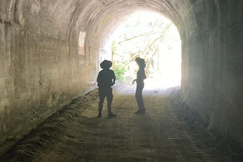 Dos personas de pie en un túnel con una salida luminosa. 3