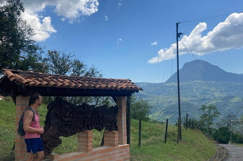 Una persona parada bajo un letrero con una montaña al fondo. 2