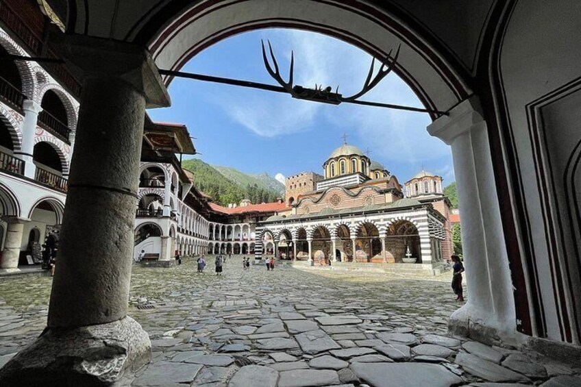 A courtyard with stone paving, arches, and a building with domed architecture. 1