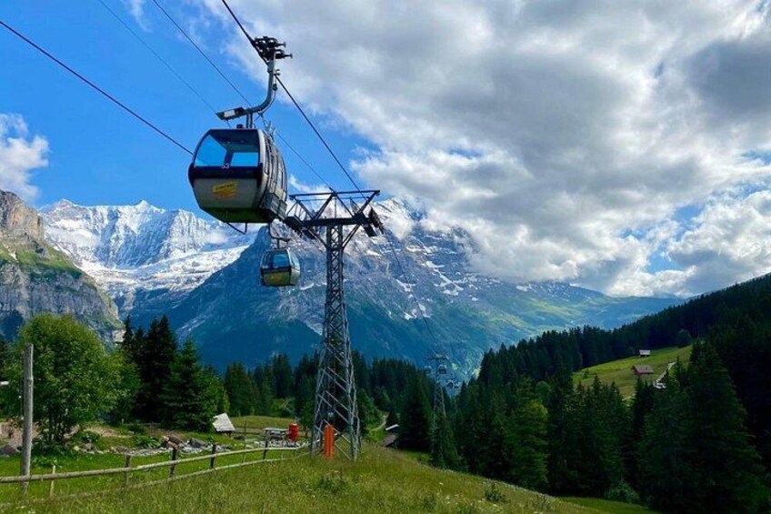 A cable car in a mountainous area with a clear sky and snow-capped peaks in the background. 3