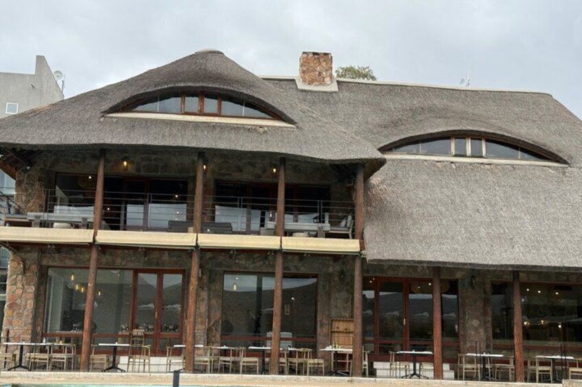 A building with a thatched roof, large windows, and a pool. 5