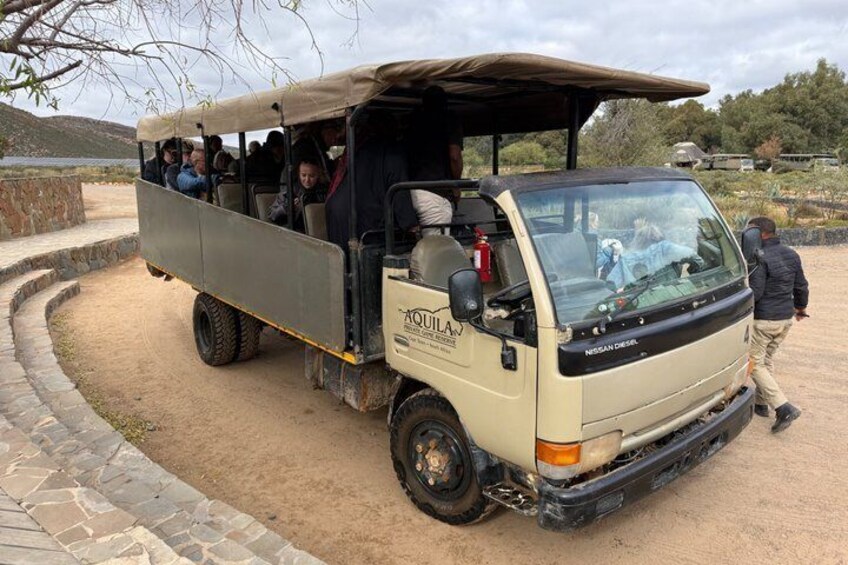 A safari vehicle with passengers, parked on a dirt path with stone curbs. 3