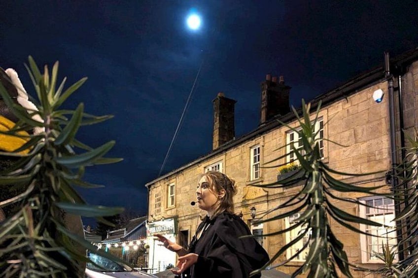 A person standing outdoors at night with a building in the background. 2