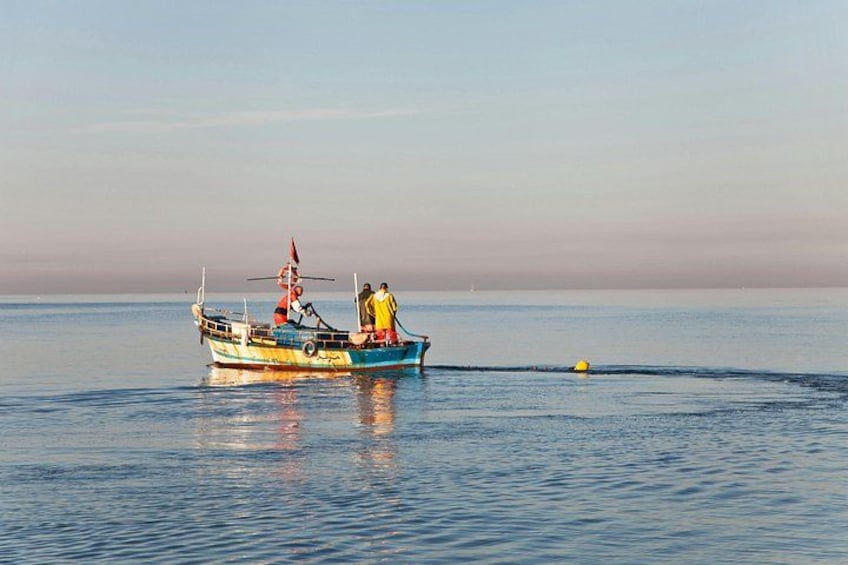 Een boot met twee personen op het water, een heldere lucht en een rustige zee. 3