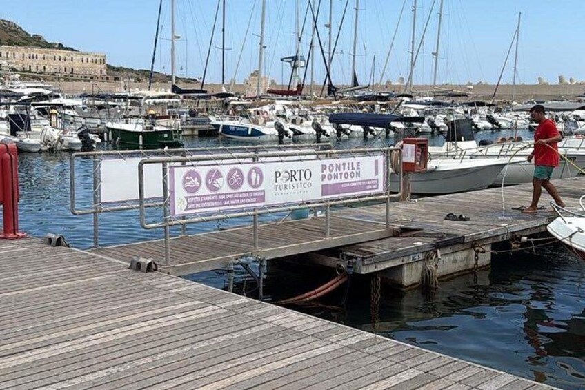 Un porto turistico con imbarcazioni ormeggiate, un molo in legno e un cartello che recita 'PONTOON TURISTIC'. 4