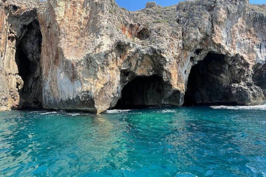 Una costa rocosa con una gran formación parecida a una cueva y agua azul cristalina. 3