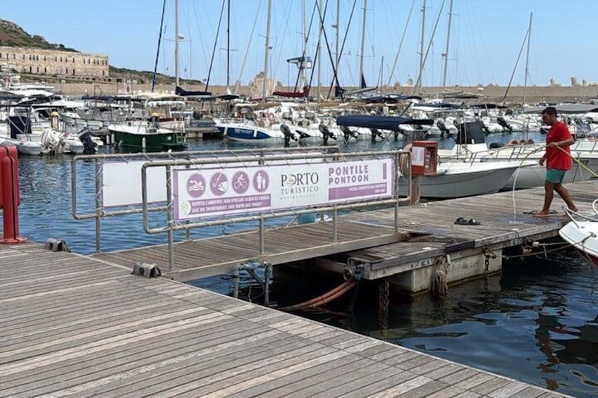 A marina with boats docked, a wooden pier, and a sign for 'PONTOON TURISTICO.' 3