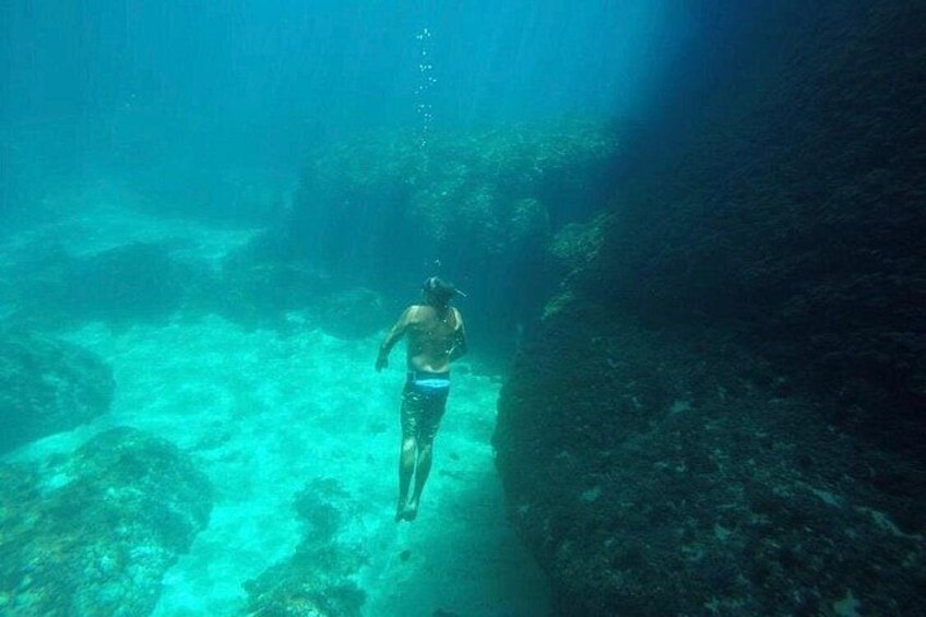 A diver swimming underwater in a clear blue water body. 4