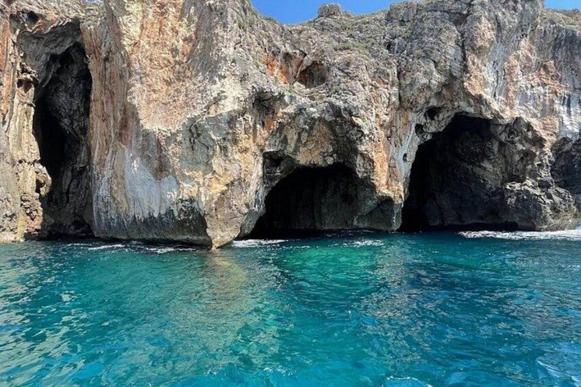 Una costa rocciosa con un'ampia apertura di una grotta e acqua cristallina color turchese. 3