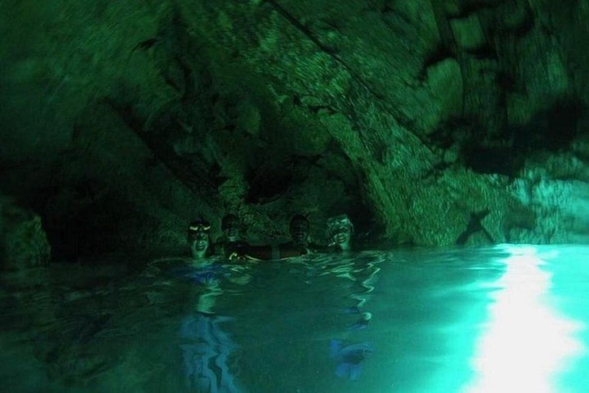 A cave with stalactites and stalagmites, and a pool of water reflecting light. 2
