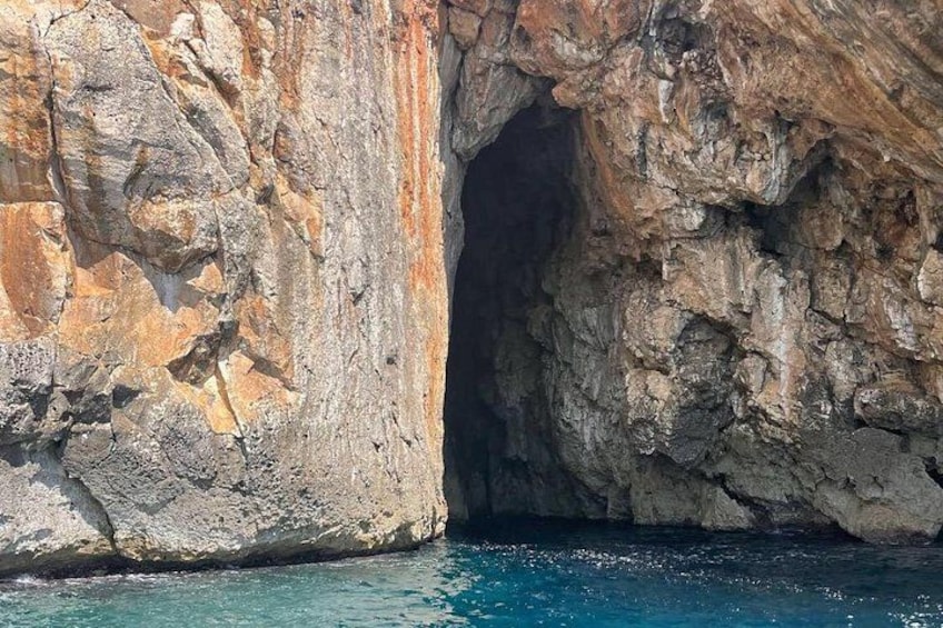 Entrada a una cueva costera rocosa con agua azul cristalina. 2
