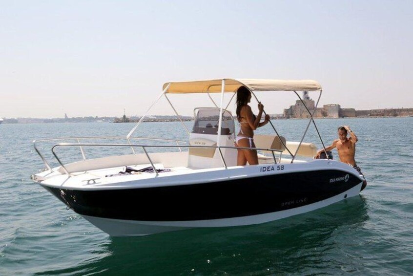 Un pequeño barco motor llamado IDEA 56 en aguas tranquilas, con un horizonte urbano de fondo. 4