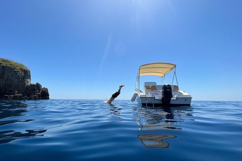 Una persona se sumerge en el agua cerca de un barco en un día despejado. 1