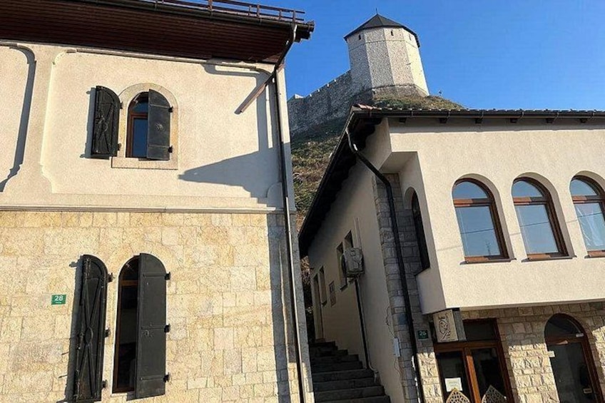 A building with a stone facade, a chimney, and a staircase leading to a second level. 2