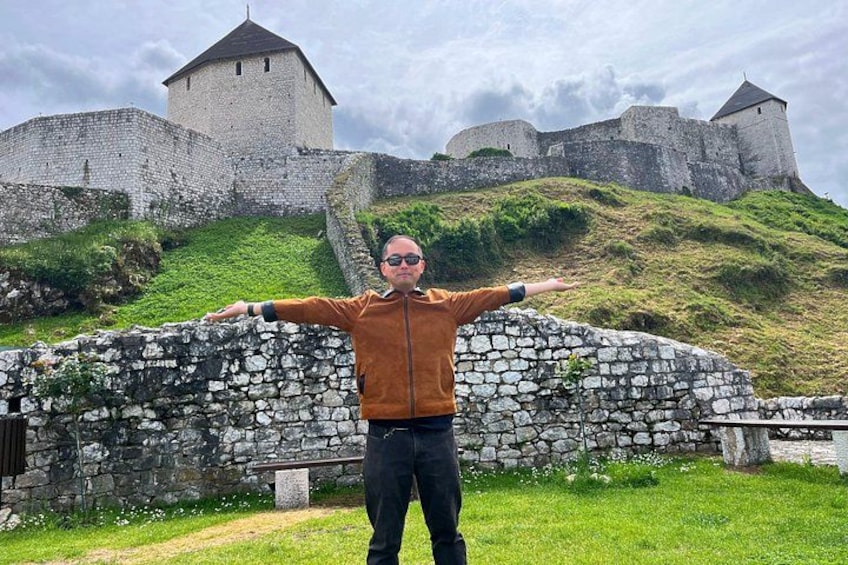 En person som står framför en stenmur med ett slott i bakgrunden. 2